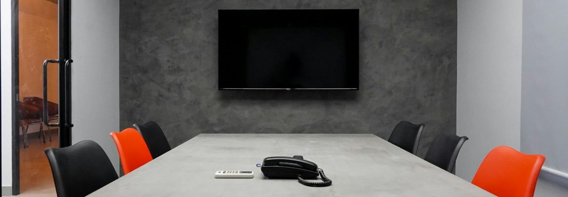 A moving professional securely installing a large TV onto an office wall mount.